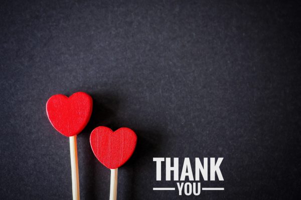 The words thank you message and two red heart on the black paper background. top viwe, flat lay with copy space. Greeting card.